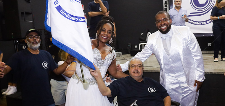 Almir Munhoz, diretor financeiro, posa ao lado do casal de Mestre-Sala e Porta-Bandeira da Mocidade Alegre