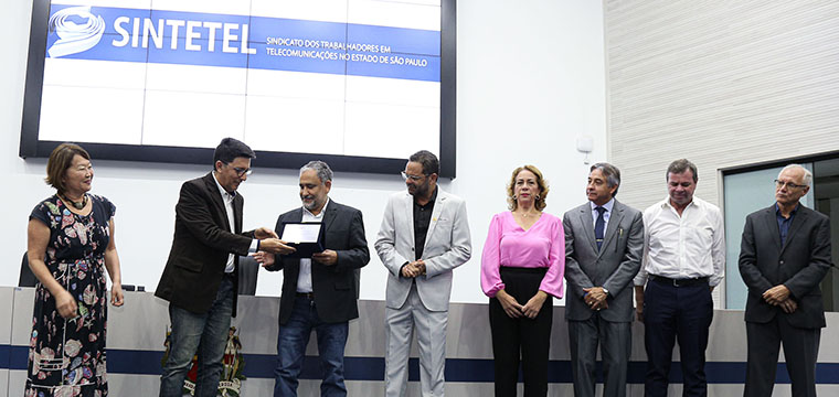 Gilberto Dourado, presidente do SINTETEL, recebe das mãos do vereador José Luiz, a placa em homenagem aos 81 anos do Sindicato